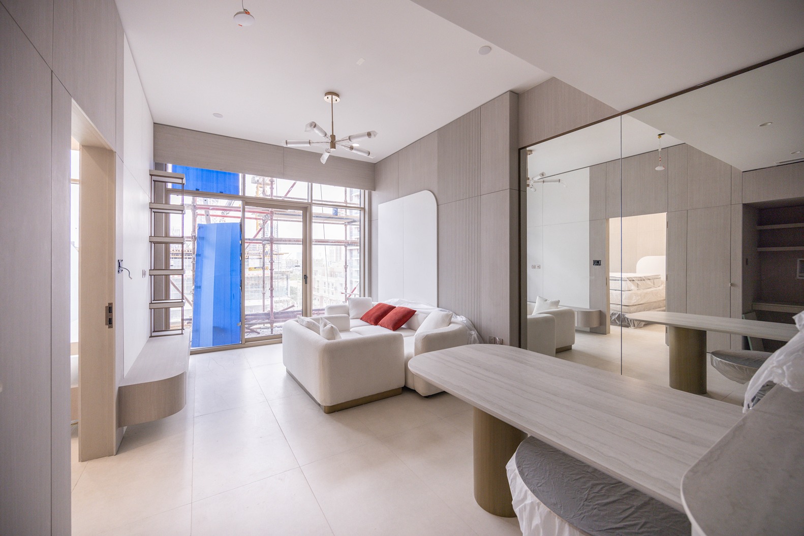 Pearl House By Imtiaz A modern, minimalist interior featuring a sofa with red cushions, a coffee table, and large windows.